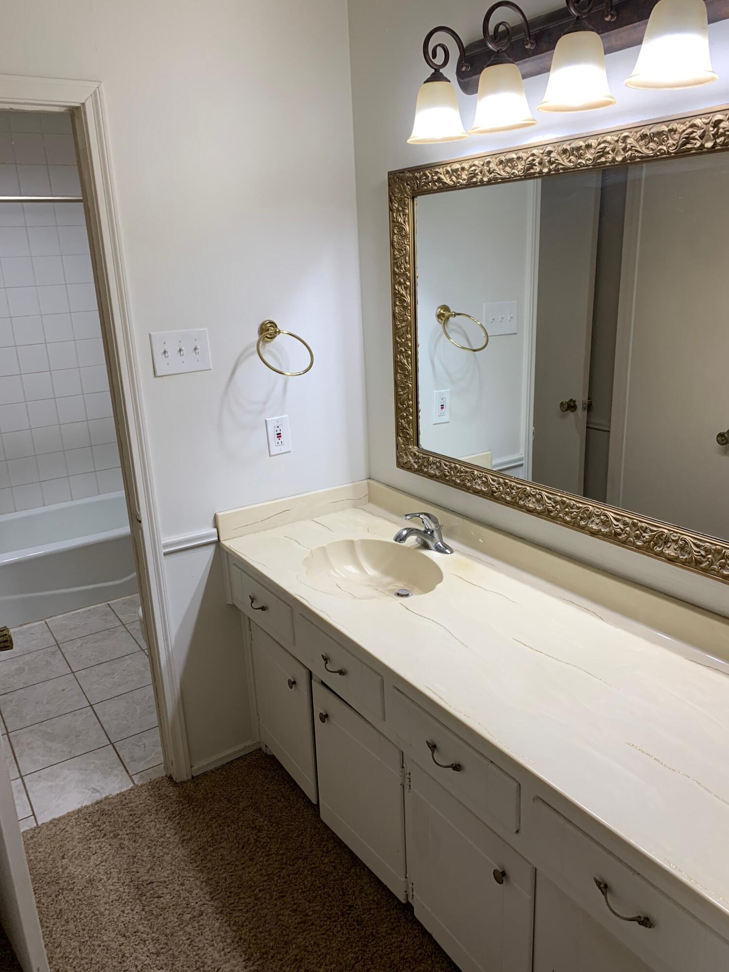 3216 74th Street, Unit B Lubbock, TX 79423 - Photo 5 of 11 a bathroom with a granite countertop sink and a mirror