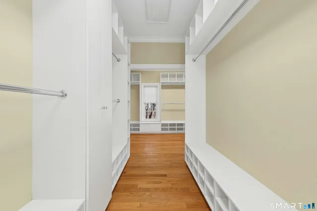 a view of a hallway with wooden floor and a bathroom