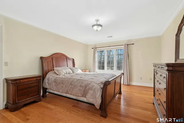 a bedroom with a bed next to a large window with wooden floor