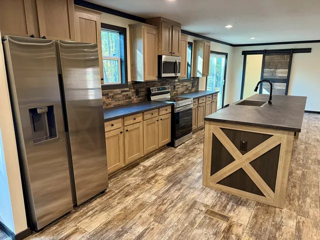 a kitchen with stainless steel appliances granite countertop a refrigerator a stove and a sink