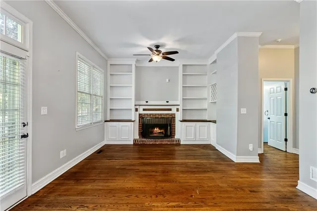 a view of a livingroom with a fireplace a ceiling fan and windows
