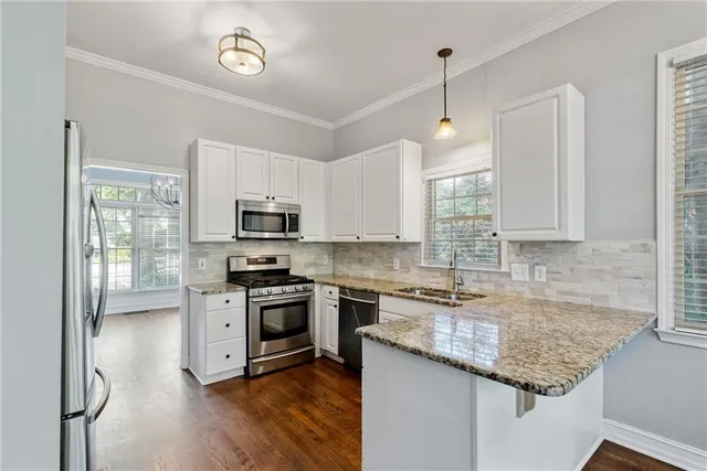 a kitchen with stainless steel appliances granite countertop white cabinets and a stove top oven