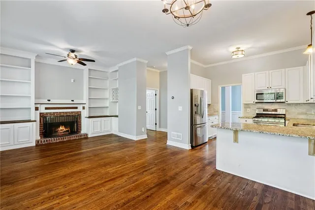 a view of a livingroom with a fireplace a ceiling fan and windows