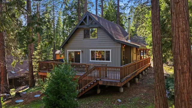 a view of a house with a small yard and wooden deck