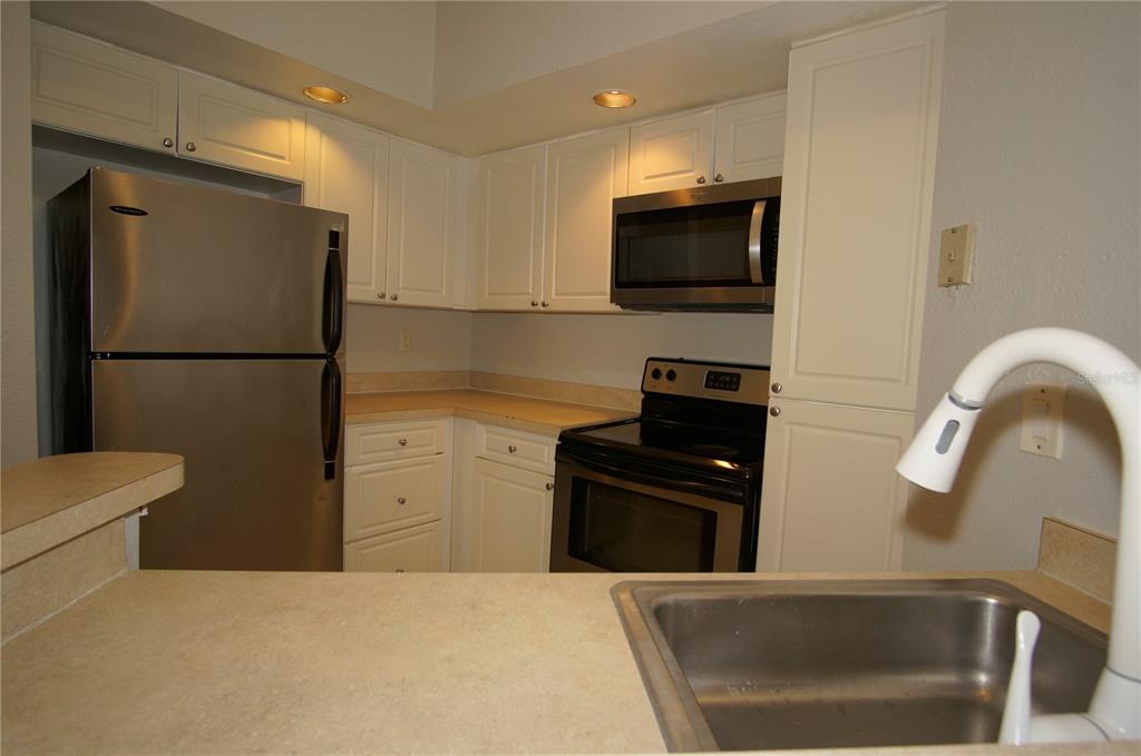 4572 Commander Drive, Unit 1237 Orlando, FL 32822 - Photo 7 of 31 a kitchen with a refrigerator and a stove top oven