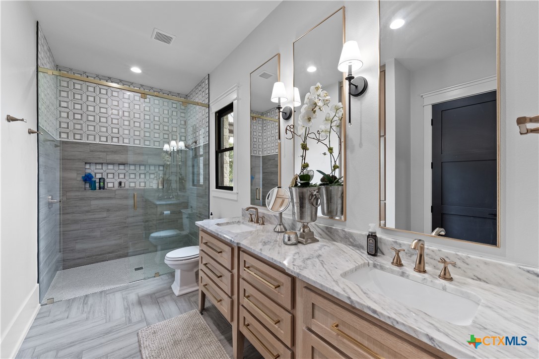 19102 Post Oak Road Bartlett, TX 76511 - Photo 17 of 43 a bathroom with a double vanity sink mirror double shower and a toilet