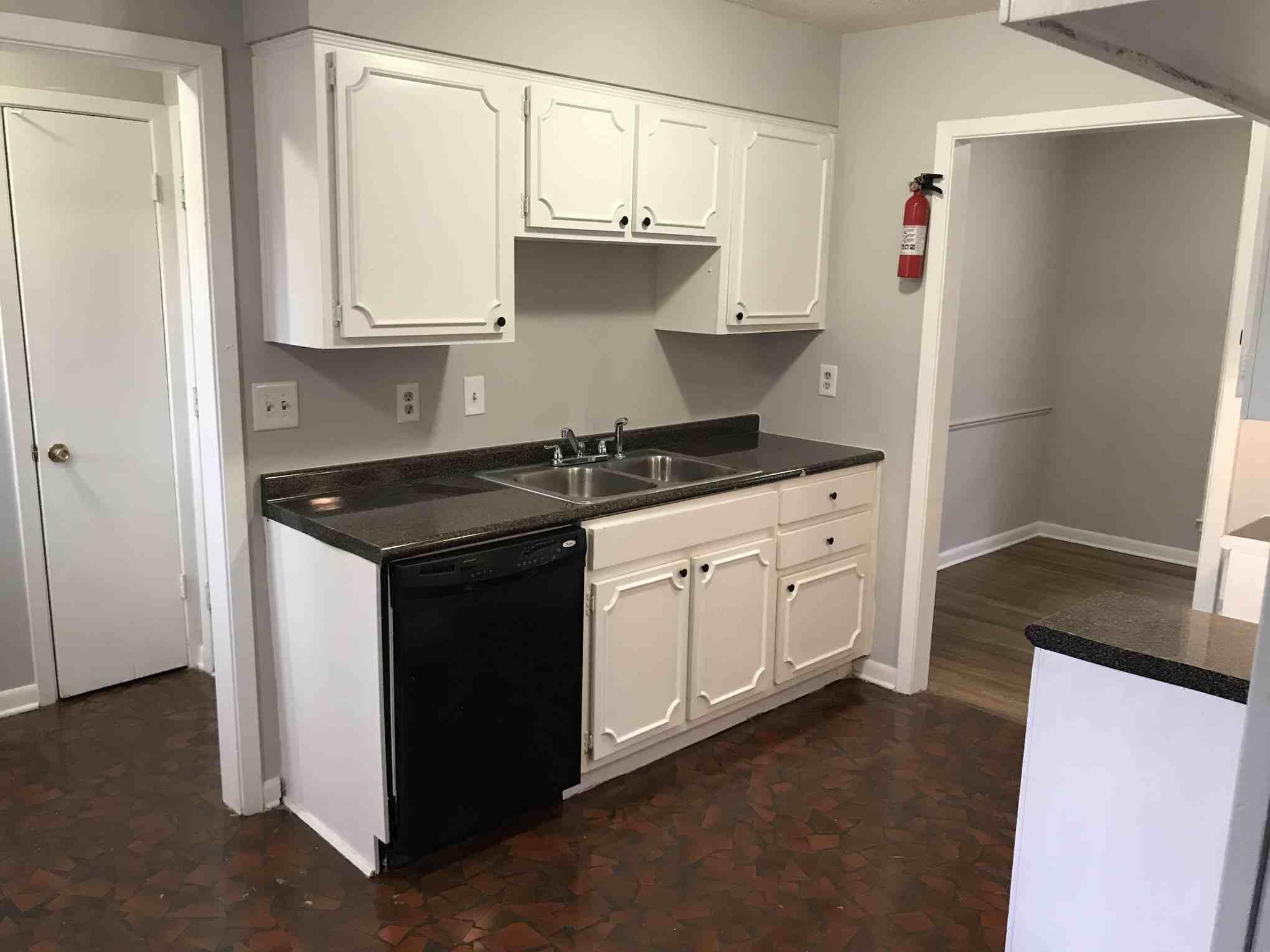 4502 Cottonwood Road Memphis, TN 38118 - Photo 2 of 16 Kitchen featuring white cabinetry with dark hardware, a dark countertop, and a double basin sink with a chrome faucet
