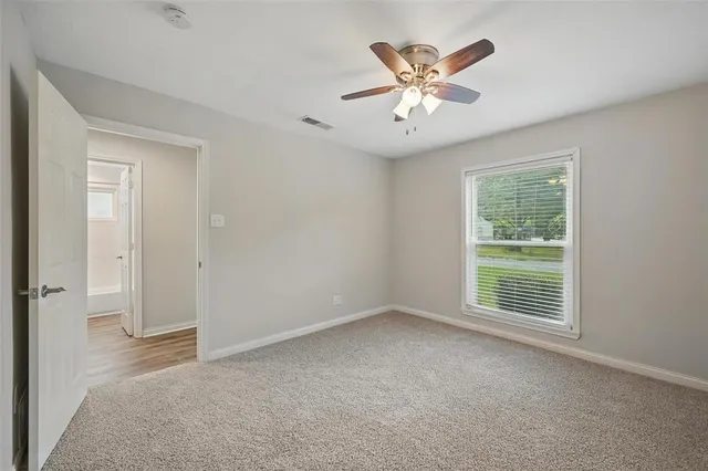 a view of an empty room with window and a ceiling fan