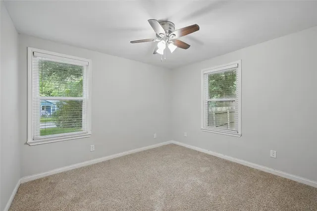 an empty room with a window and a fan