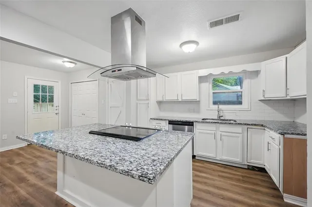 a kitchen with granite countertop a sink cabinets and wooden floor
