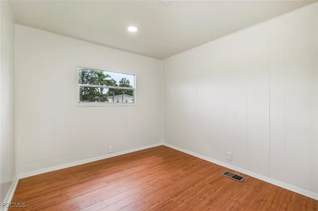 an empty room with wooden floor and window