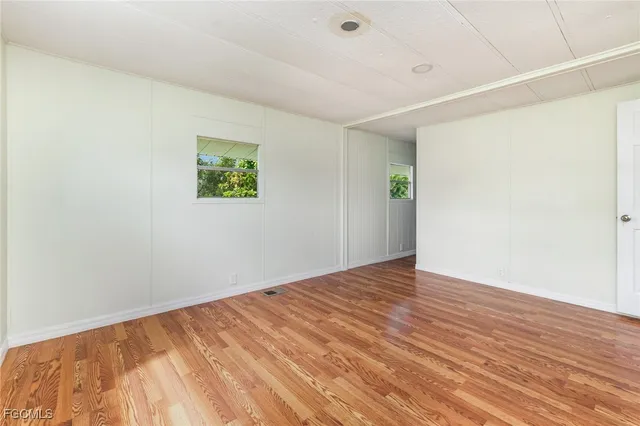 an empty room with wooden floor and window