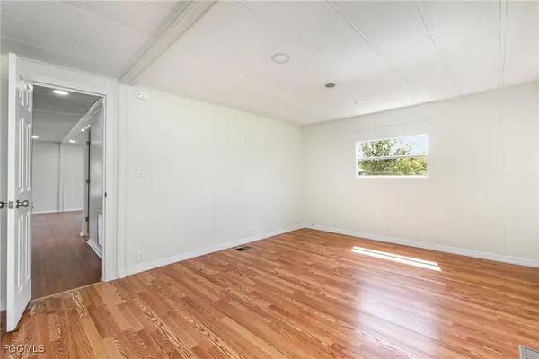 a view of a big room with wooden floor and windows