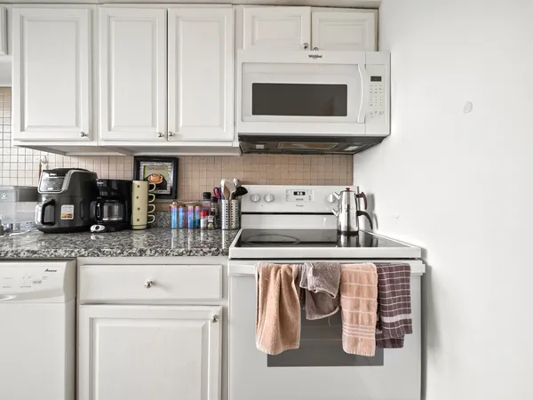 a kitchen with stainless steel appliances granite countertop white cabinets and a stove