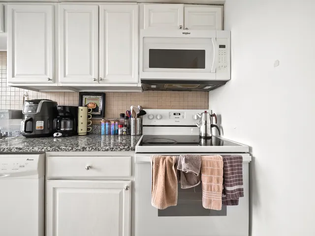 a kitchen with stainless steel appliances granite countertop white cabinets and a stove