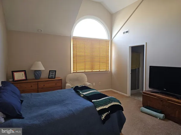 a bedroom with a large bed and a flat tv screen on a dresser