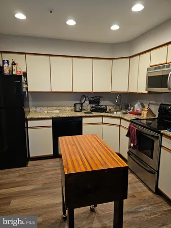 a kitchen with stainless steel appliances a stove a sink dishwasher and a refrigerator with wooden floor