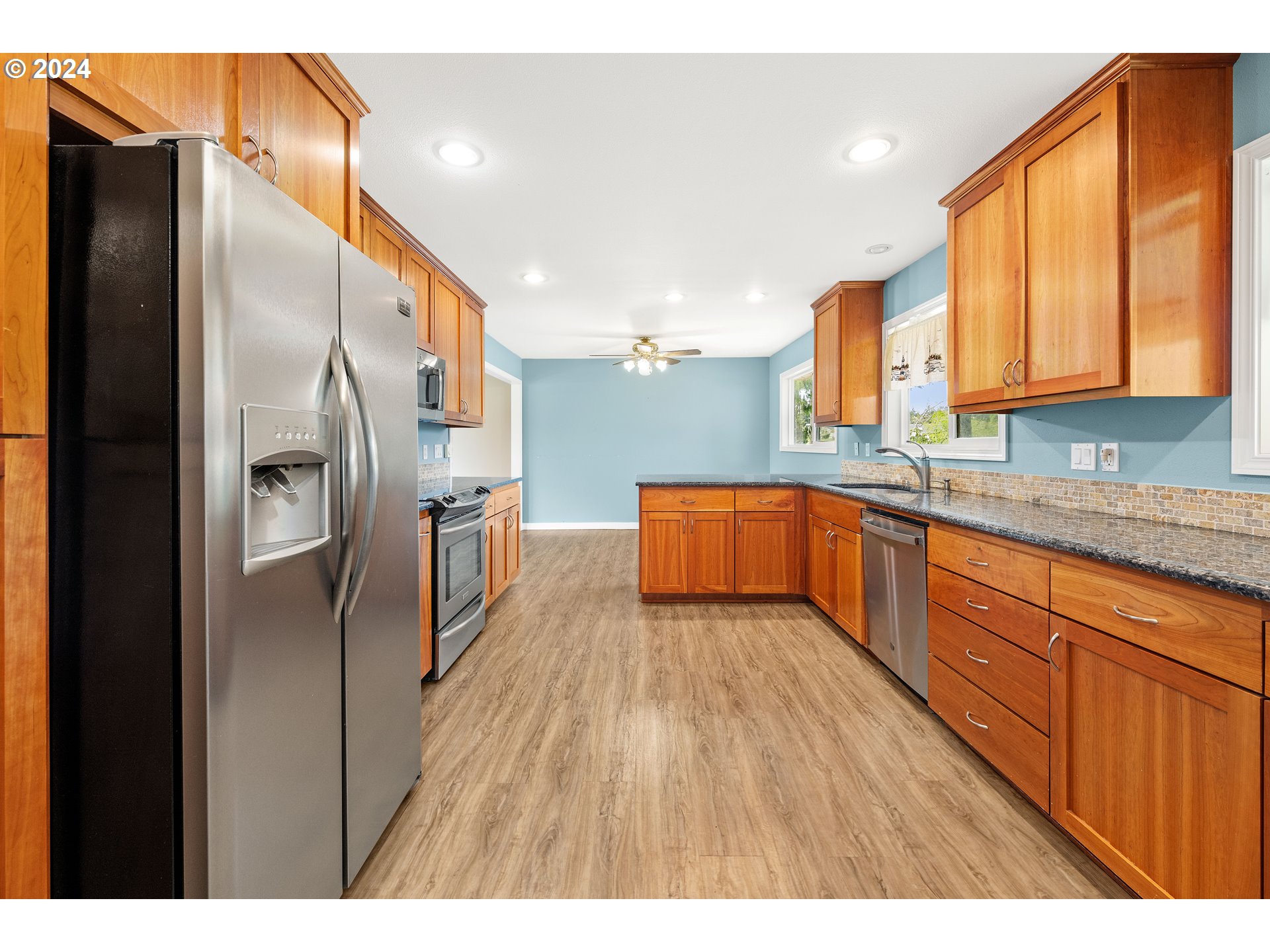 91897 Ridge Road Warrenton, OR 97146 - Photo 5 of 24 a kitchen with stainless steel appliances granite countertop a refrigerator a sink and wooden cabinets