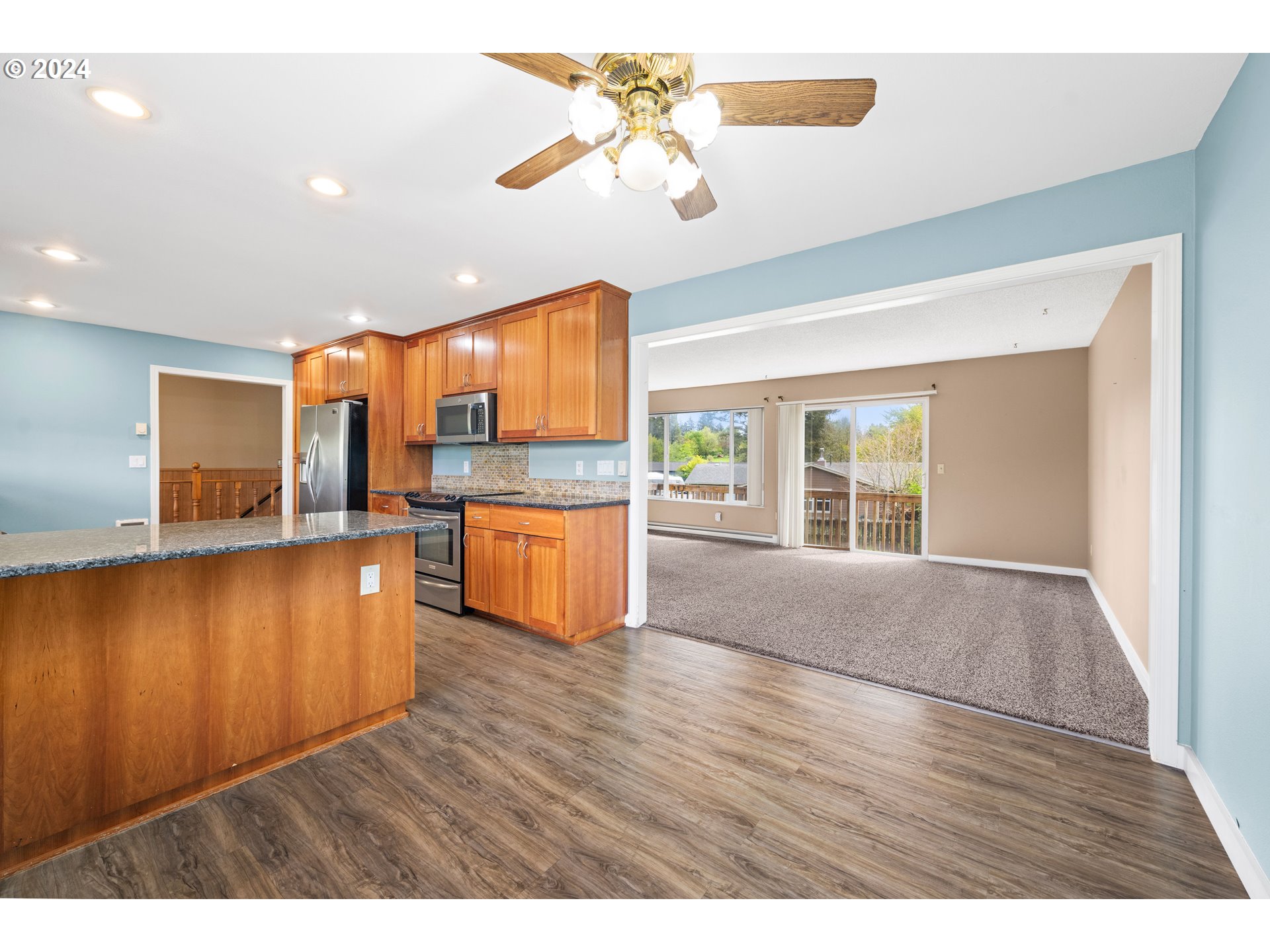 91897 Ridge Road Warrenton, OR 97146 - Photo 9 of 24 a kitchen with stainless steel appliances granite countertop a refrigerator a sink dishwasher a stove and a dining table with wooden floor