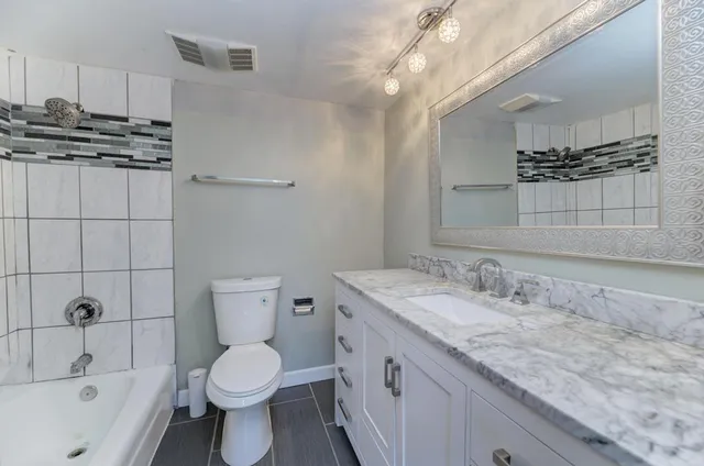 a bathroom with a granite countertop sink a toilet and shower
