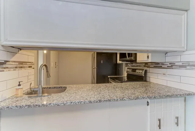 a kitchen with granite countertop a sink a stove and stainless steel appliances