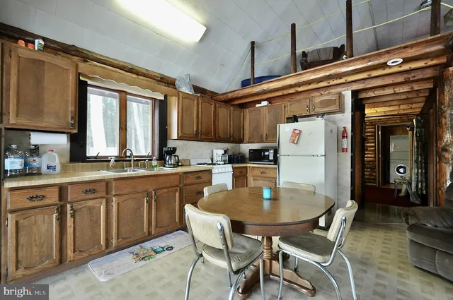 a kitchen with a dining table chairs and refrigerator