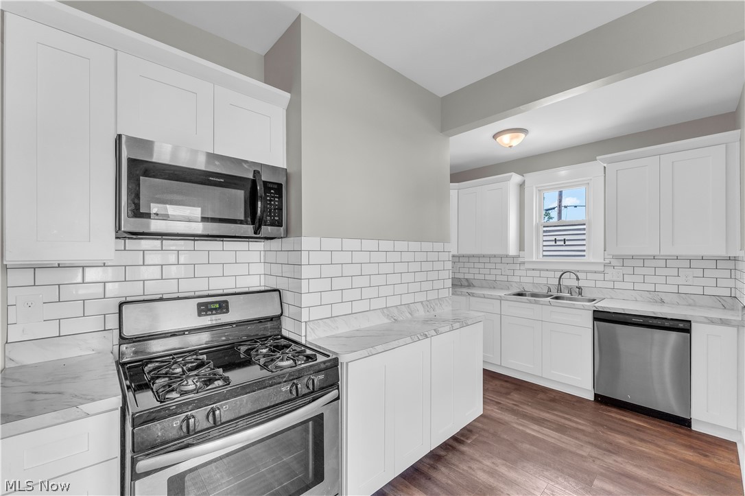 3506 Riverside Avenue Cleveland, OH 44109 - Photo 14 of 31 Kitchen featuring white shaker-style cabinetry, subway tile backsplash, stainless steel appliances, marble-look countertops, and wood-finish flooring