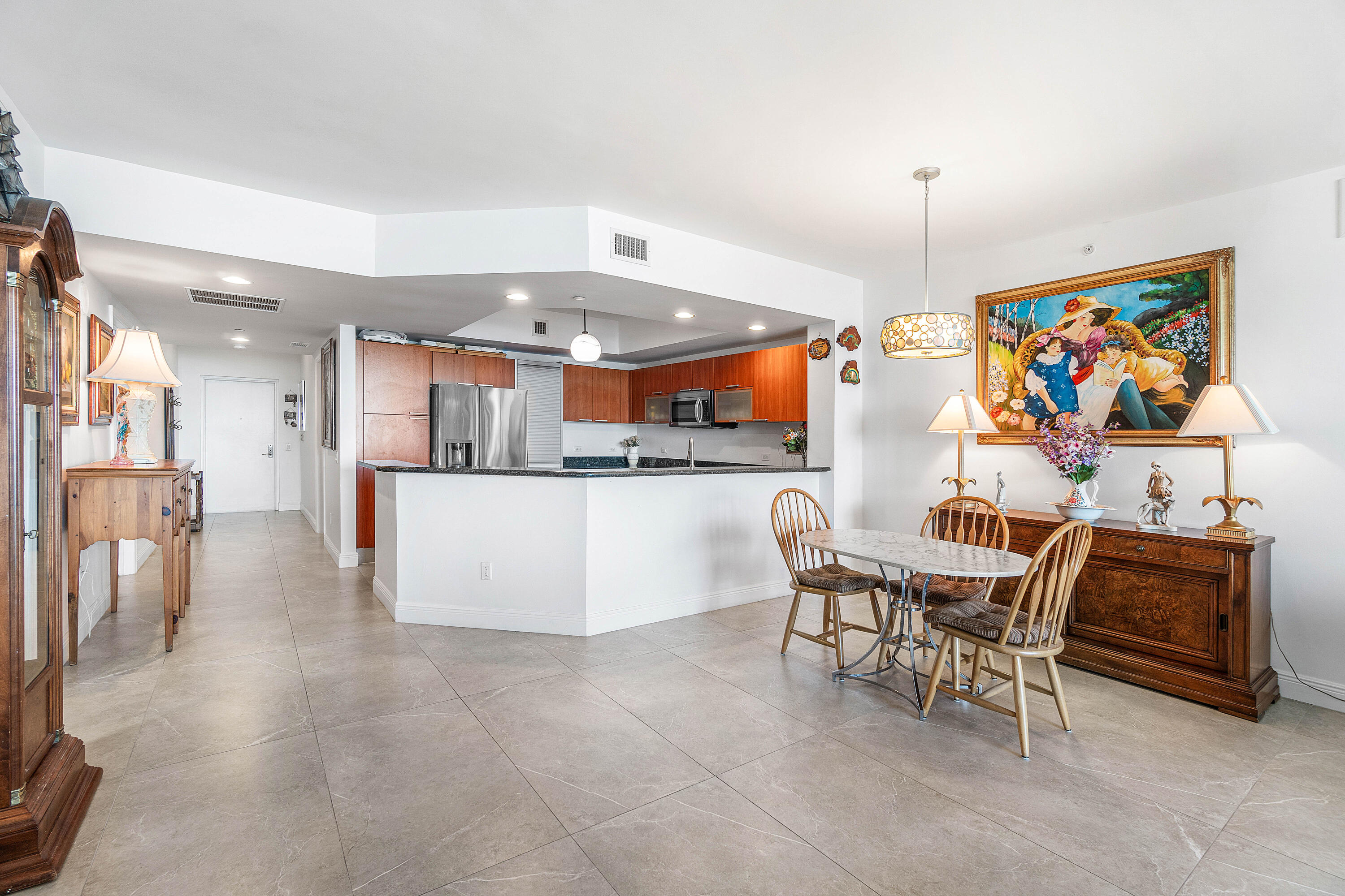 2650 Lake Shore Drive, Unit 1705 Riviera Beach, FL 33404 - Photo 5 of 35 a kitchen with stainless steel appliances kitchen island granite countertop a table and chairs in it