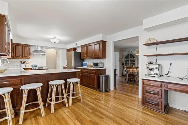 a kitchen with stainless steel appliances granite countertop a stove top oven a sink a dining table and chairs with wooden floor
