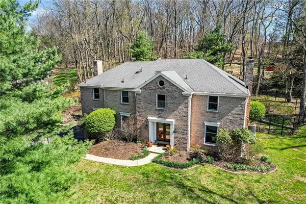 a aerial view of a house with yard and trees in the background