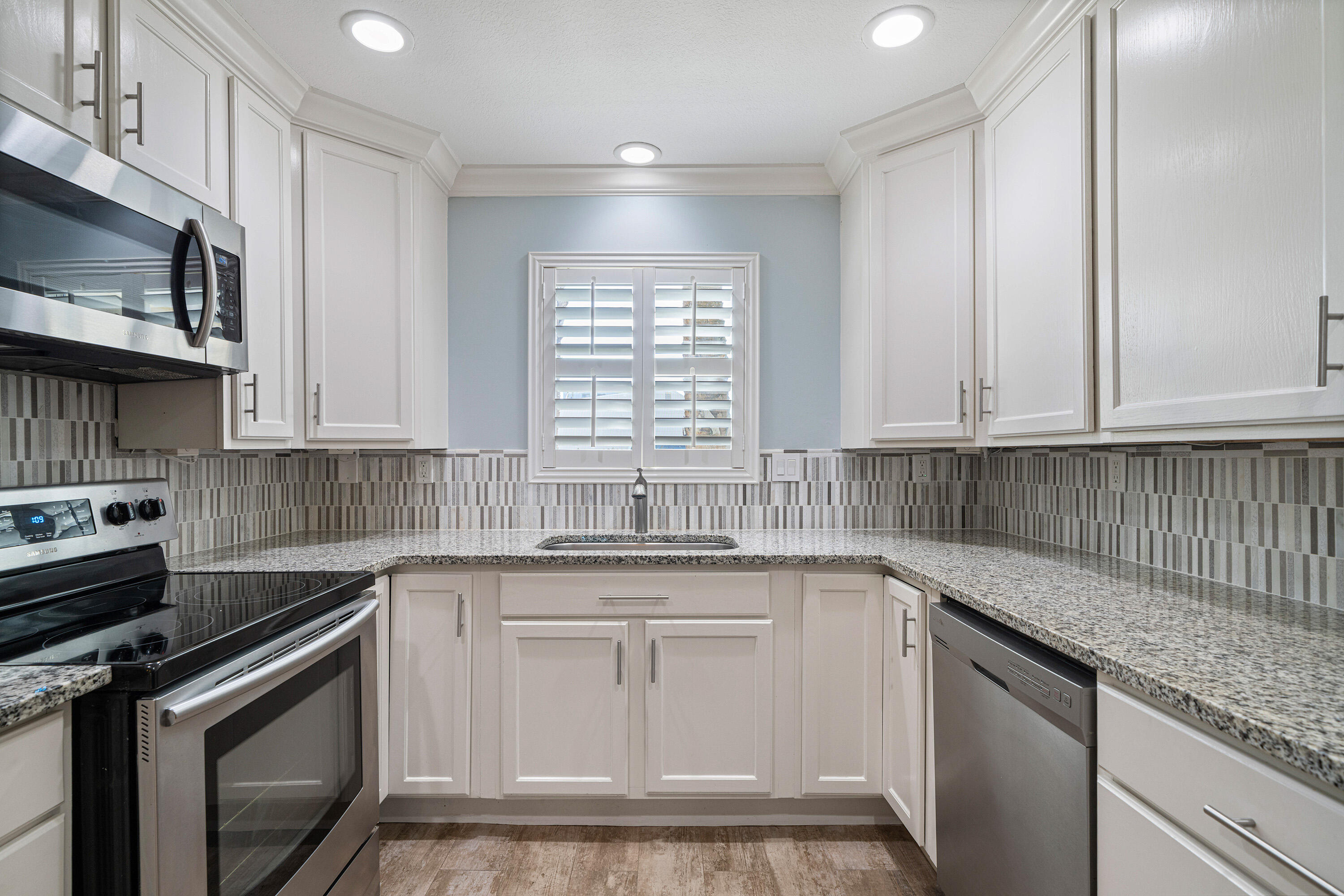 235 Pelican Place, Unit 3 Destin, FL 32541 - Photo 2 of 32 a kitchen with stainless steel appliances granite countertop a sink dishwasher a stove and a microwave oven with cabinets