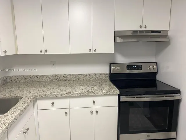 a kitchen with granite countertop white cabinets and a stove