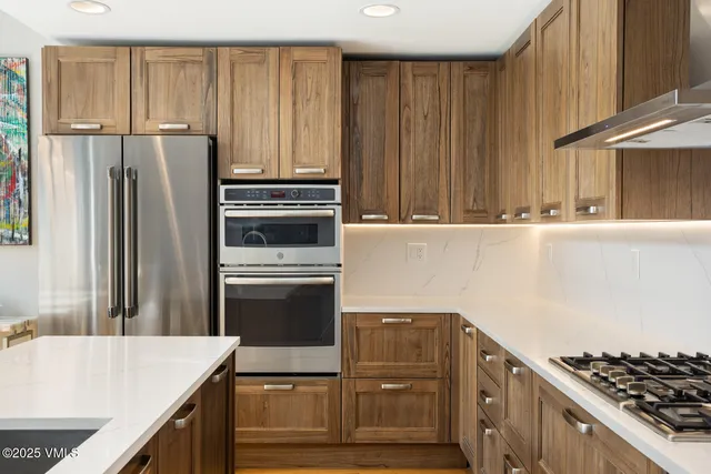 a kitchen with granite countertop a refrigerator stove and cabinets