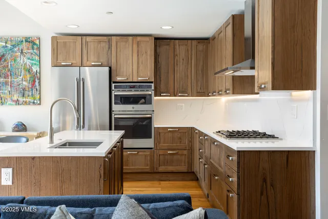 a kitchen with stainless steel appliances granite countertop a sink a stove and a refrigerator