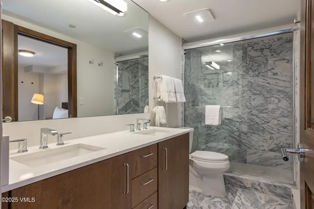 a bathroom with a sink toilet double vanity and shower