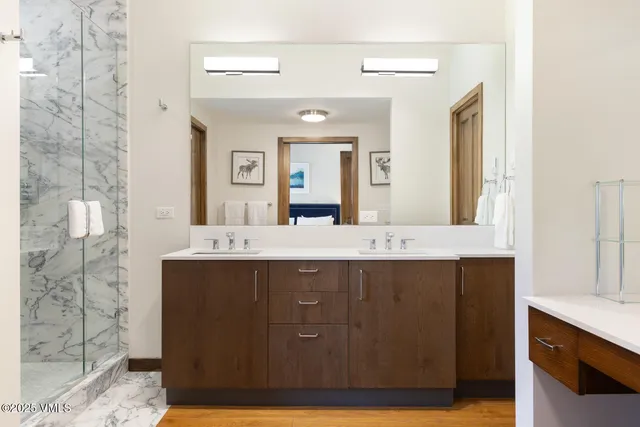 a bathroom with a granite countertop sink a mirror and shower