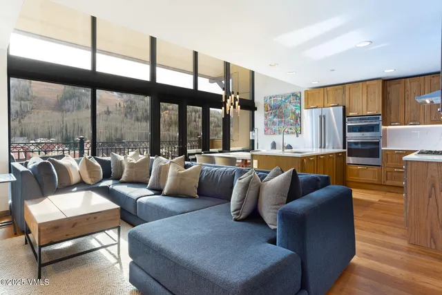 a living room with furniture kitchen view and large windows