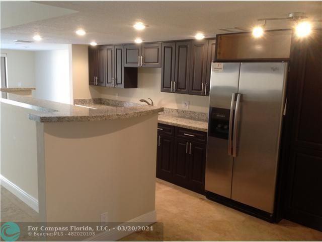 a modern kitchen with stainless steel appliances granite countertop a sink a stove and a refrigerator
