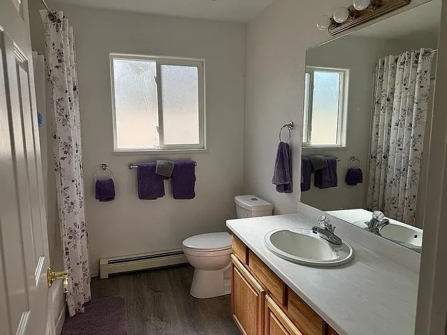 a bathroom with a granite countertop sink toilet and mirror