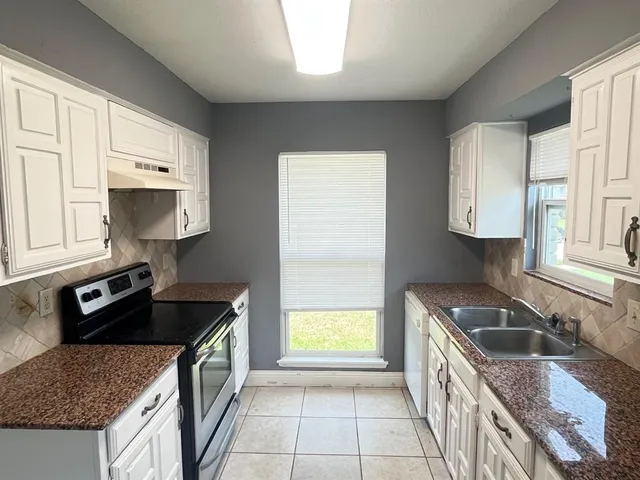 a kitchen with granite countertop a sink a stove and cabinets