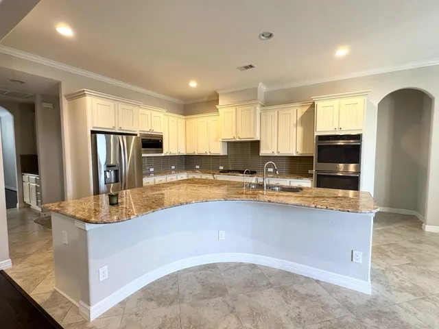 a large kitchen with granite countertop a large counter top stainless steel appliances and cabinets