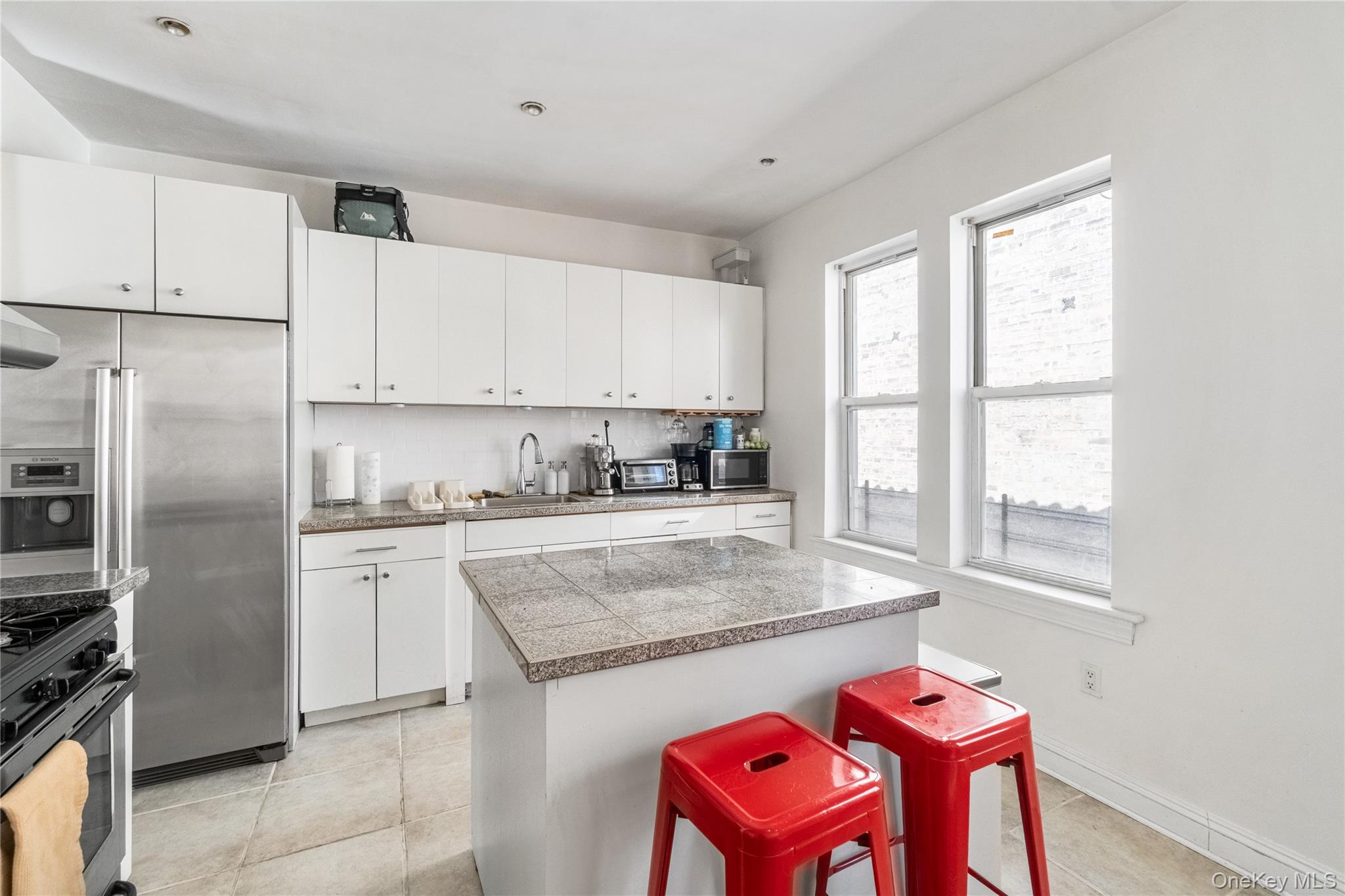 2969 Perry Avenue Bronx, NY 10458 - Photo 3 of 36 a kitchen with a refrigerator a stove a sink and white cabinets