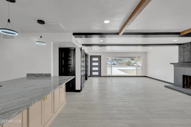 a view of an empty room with wooden floor and a kitchen