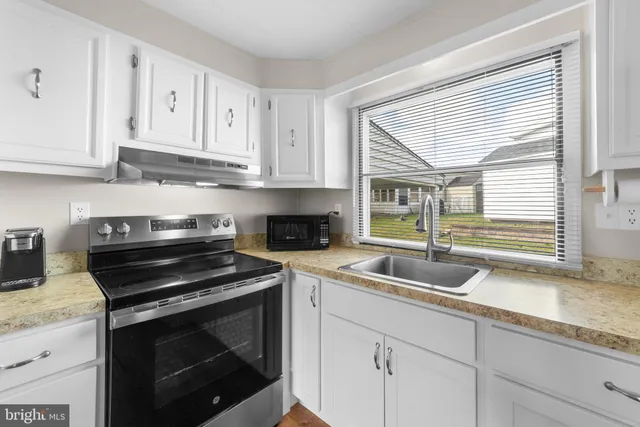 a kitchen with granite countertop a sink stove and cabinets