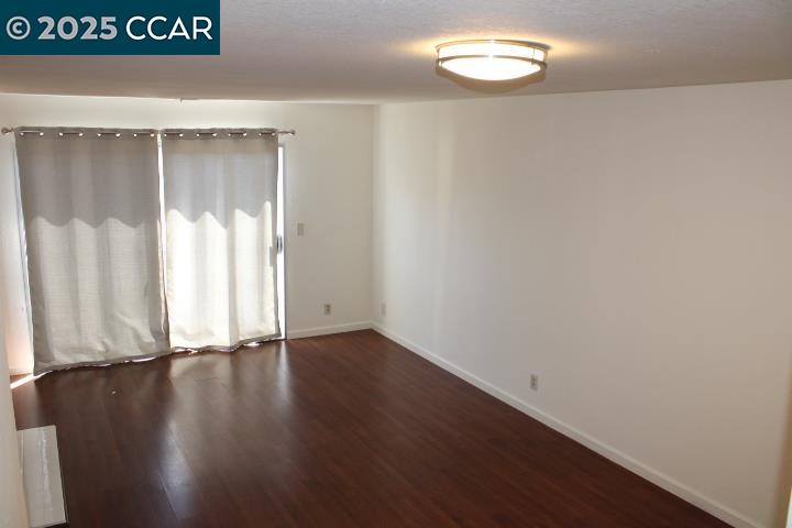 4811 Appian Way, Unit 3/5 El Sobrante, CA 94803 - Photo 3 of 27 a view of an empty room with wooden floor and a window