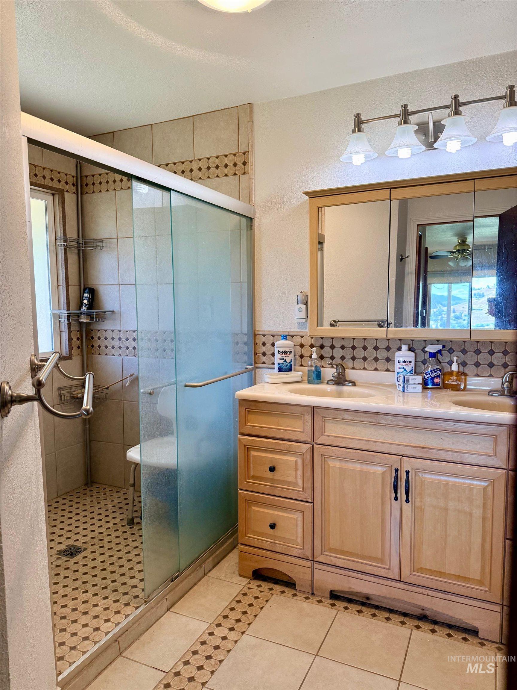 35322 River Road Lenore, ID 83541 - Photo 19 of 42 Bathroom featuring a spacious walk-in shower with glass enclosure, dual vanity with undermount sinks, and tile flooring with decorative accents