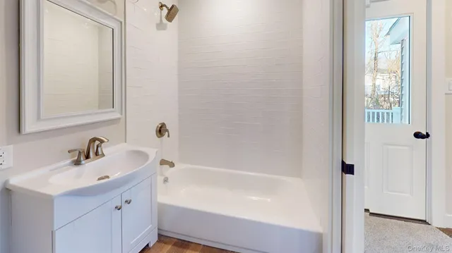 a white bath tub sitting next to a white sink and a mirror