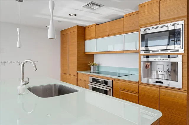 a kitchen with stainless steel appliances granite countertop a sink a stove and a wooden cabinets