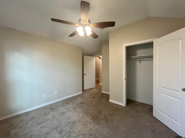 a view of an empty room with a chandelier fan