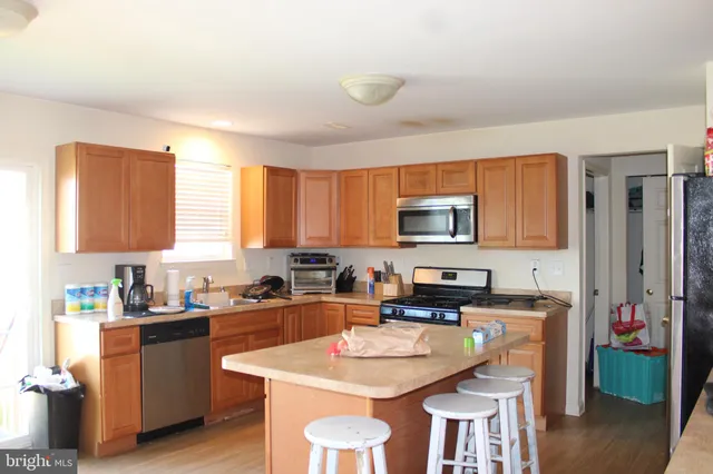 a kitchen with stainless steel appliances granite countertop a sink a stove a refrigerator cabinets and chairs